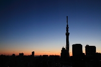 旅行で泊まったザ・ゲートホテル雷門の屋上テラスからの著作権フリーの写真素材。横位置の写真の中央やや右に東京の新観光名所、東京スカイツリーがシルエット姿で綺麗にオレンジからネイビーブルーのグラデーションのかかった綺麗な朝焼けの空に浮かび上がっている。